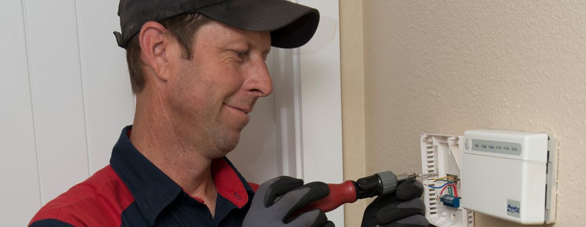 electrician working on home thermostat