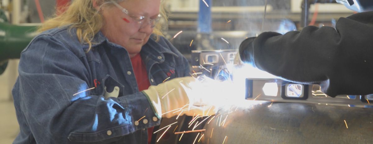 student grinds pipe in pipefitting course