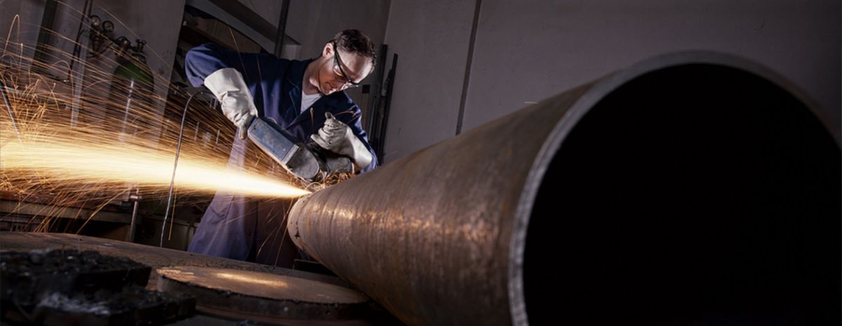 welder cutting a steel pipe